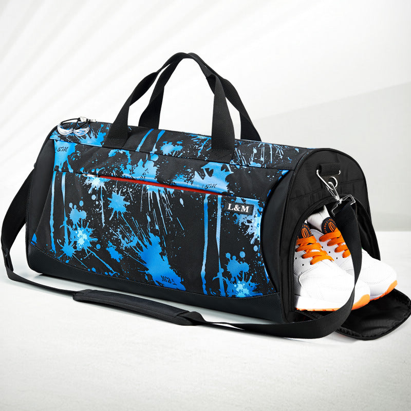 black duffel bag with blue splatter design and orange and white shoes peeking out on a light gray background