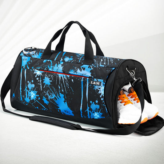Black duffel bag with blue splatter design and orange and white shoes peeking out on a light gray background